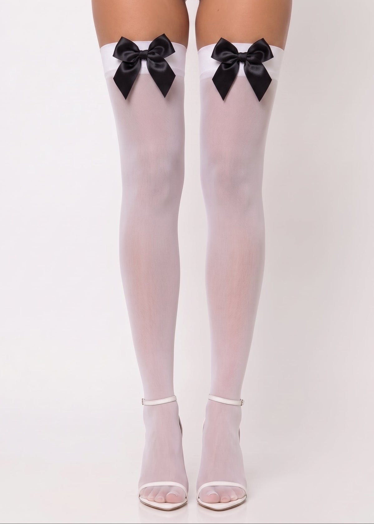 White thigh-high stockings with large black bow accents at the top, shown on a model's legs against a plain white studio background.